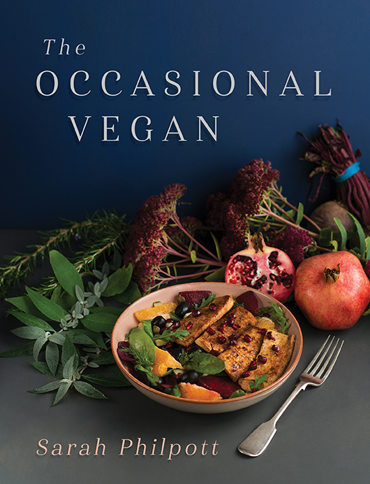 This cover shows a vibrant bowl of food surrounded by colourful ingredients against a rich blue background. The text reads: The Occasional Vegan, Sarah Philpott