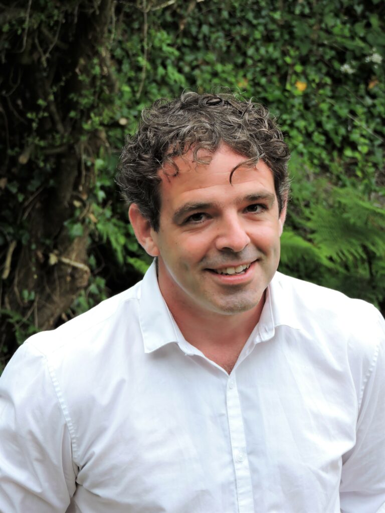 Photo of Eoghan Walls standing outside and smiling at the camera.