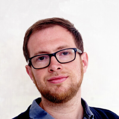 Photo of Dai George. He is wearing a blue shirt and dark rimmed glasses.