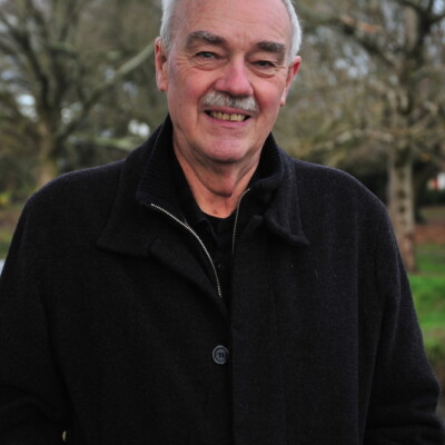 John Briggs is a white man with short hair and a moustache. He is wearing a dark winter coat and is standing outside.