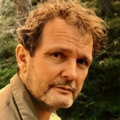 Richard Gwyn is a white man with short brown hair. He is looking over his shoulder towards the camera.
