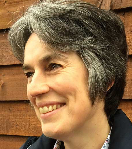 Close up photo of Ilse Pedler standing outside. She is looking slightly away from the camera and is smiling.