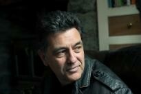 Photo of Paul Henry looking over his shoulder away from the camera. He is wearing a dark leather jacket.