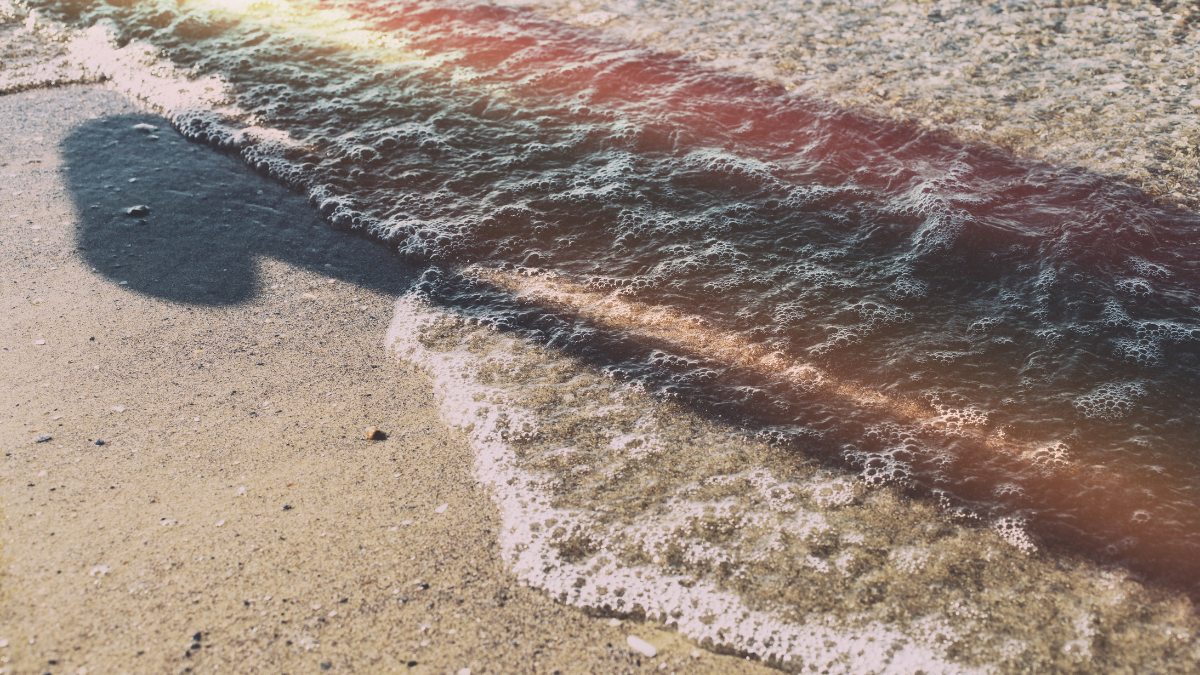 Photo of an abstract shadow stretching out across a lapping wave
