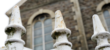 Close up photograph of painted metal railings outside a chapel building.