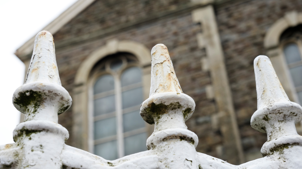 Close up photograph of painted metal railings outside a chapel building.