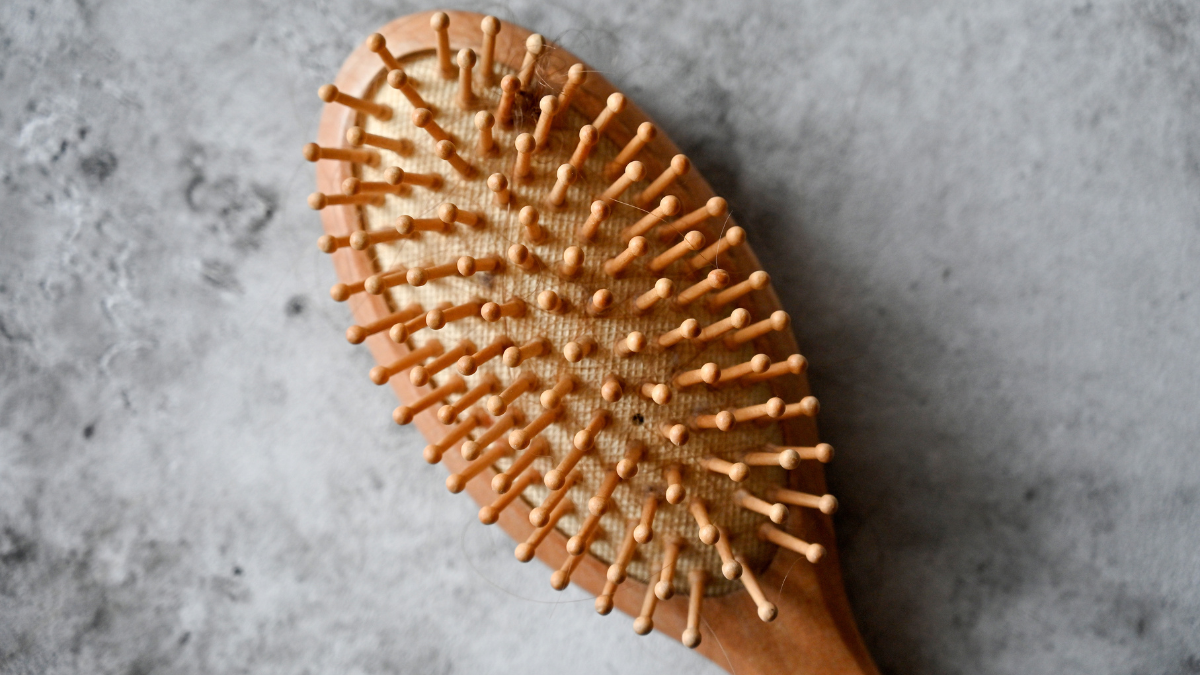 A wooden hairbrush laying on a grey worktop