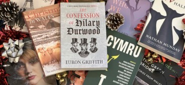 Photograph of lots of Seren non-fiction titles including Christmas in Wales, Cymru and I and The Confession of Hilary Durwood lying in a scattered pile surrounded by festive decorations.