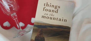 Photograph of Things Found on the Mountain laid out on a blanket with a lit candle and a small bottle of wine