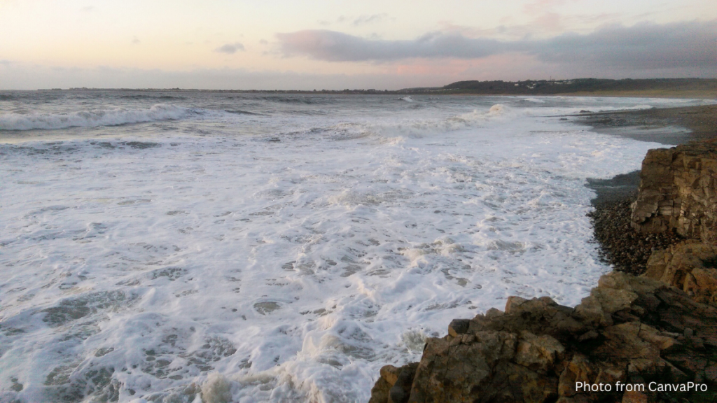 Photo of foamy waves washing against a rocky shore