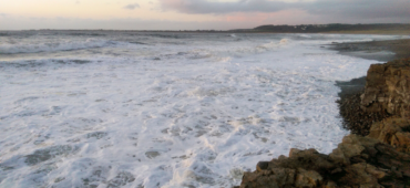 Photo of foamy waves washing against a rocky shore