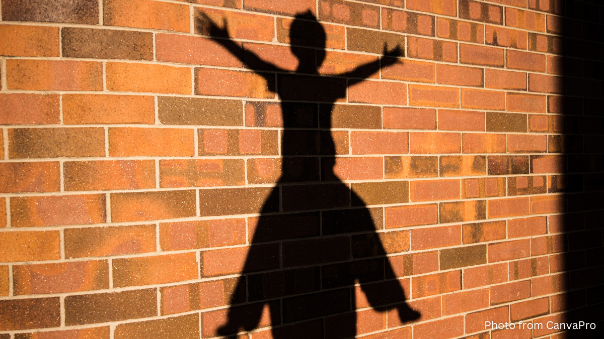 Shadow of a child sitting with their arms and legs outstretched on top of someone's shoulders