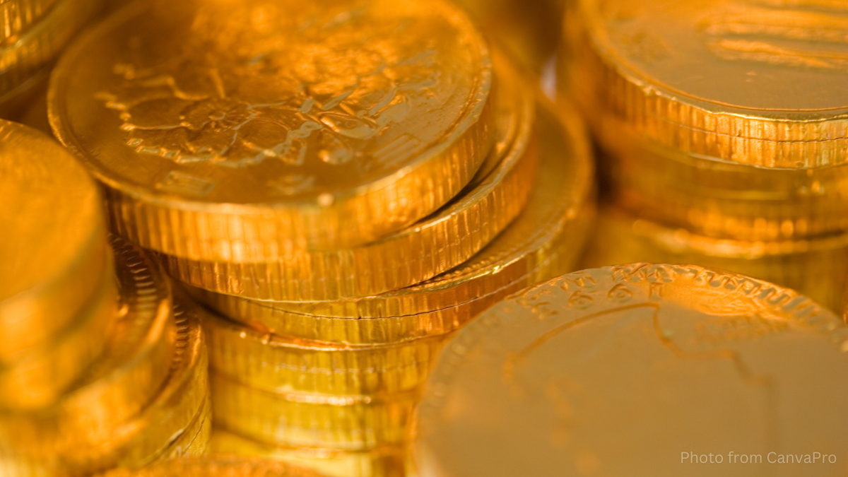 Close up photo of stacked, chocolate coins wrapped in shiny golden foil.