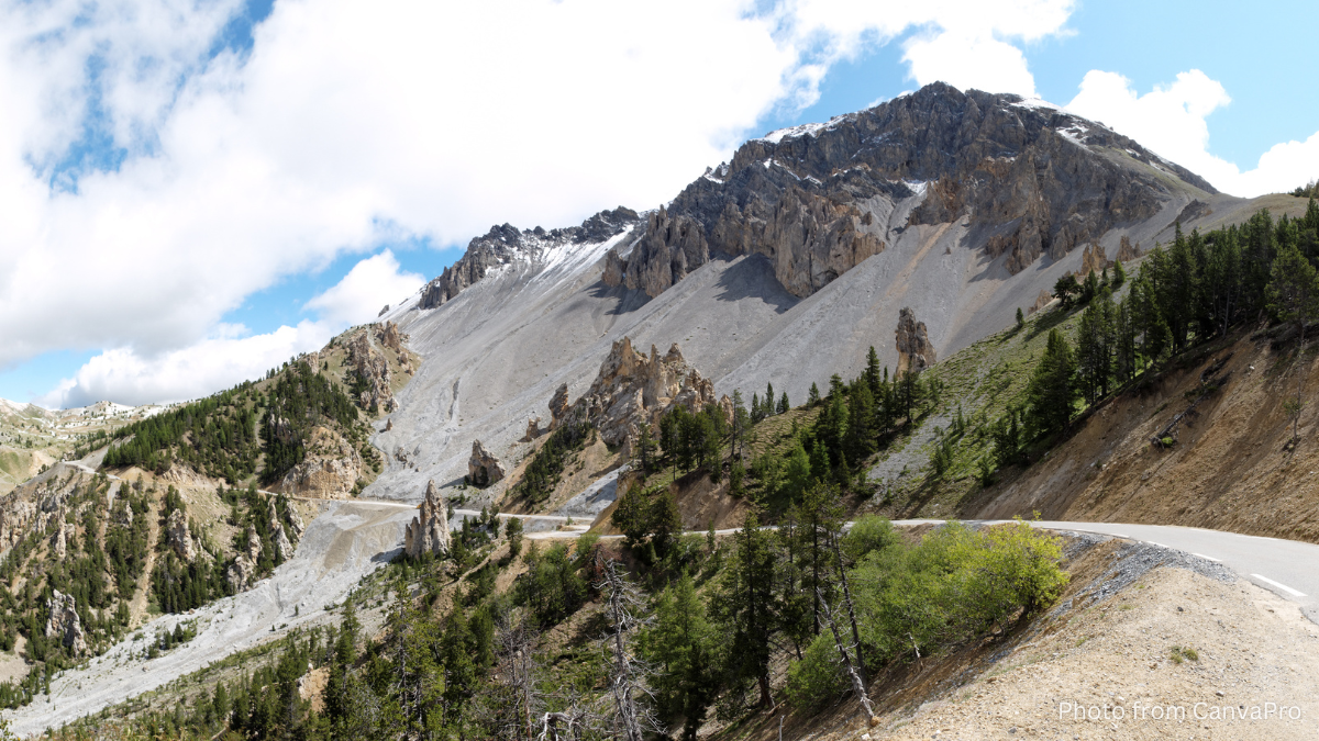 Photo of a dusty road bending to the left and disappearing into rocky mountains