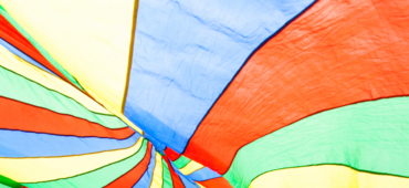 Close up of a colourful silk parachute open with sunlight streaming through it