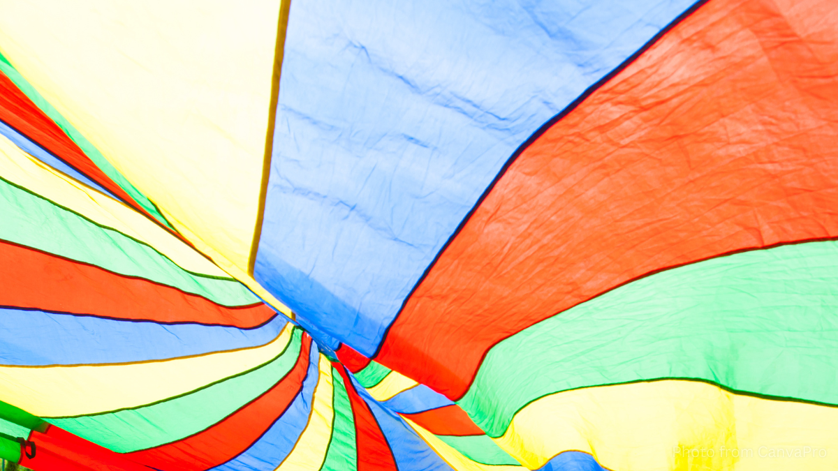 Close up of a colourful silk parachute open with sunlight streaming through it