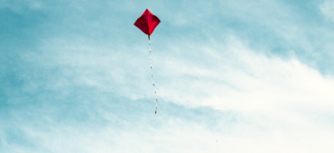 A red kite floating high in a blue sky