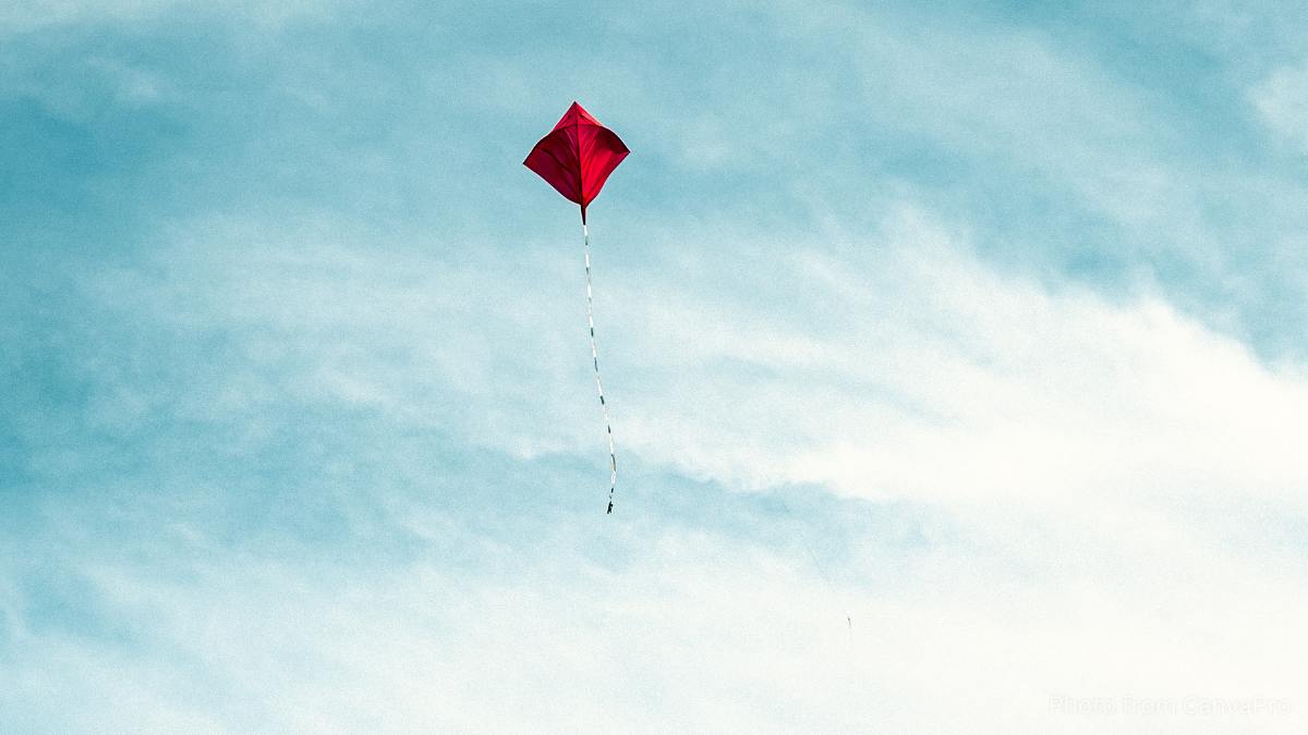 A red kite floating high in a blue sky
