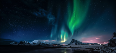 The green smudge of the Northern Lights hanging over an icy lake and lonely mountain.