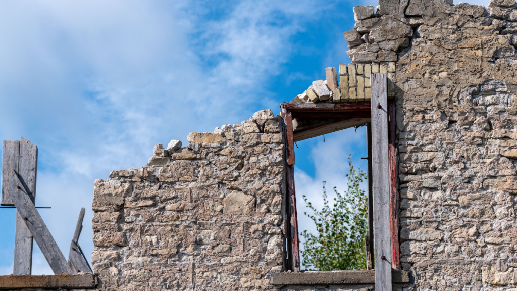 Photo depicting the ruined wall and empty window of a crumbling building