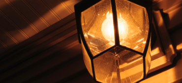 Close-up photo of a glass porch light shining in the dark.