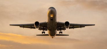 Photo of a plane coming into land against a golden sky.