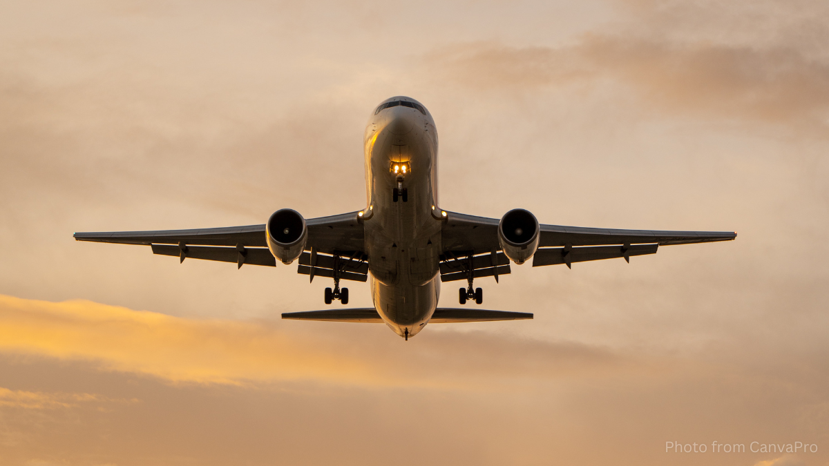 Photo of a plane coming into land against a golden sky.