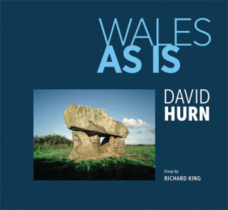 This cover has a blue background, framing a picture of a neolithic stone plinth propped up by concrete blocks. The text reads: Wales As Is. David Hurn. Essay by Richard King.