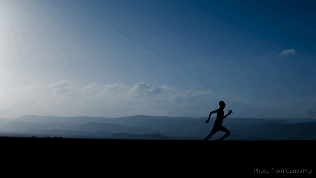 Photo of a lone runner running across a fell as the sun rises over distant mountains.