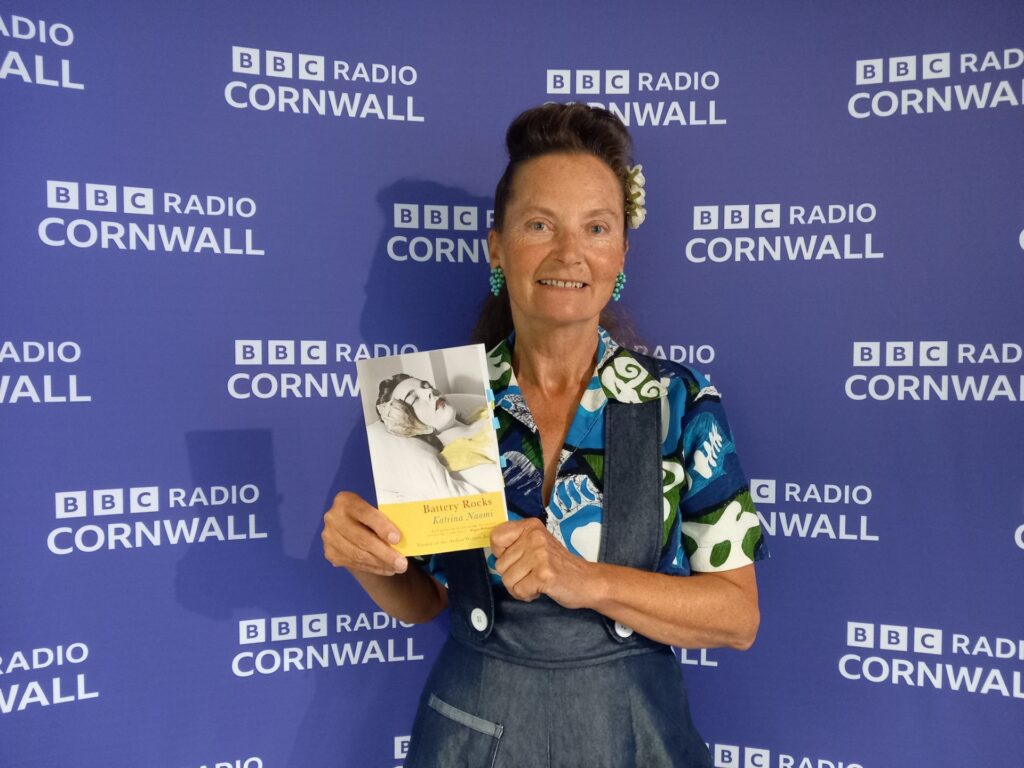 Photo of Katrina Naomi holding up a copy of her book taken at BBC Radio Cornwall.