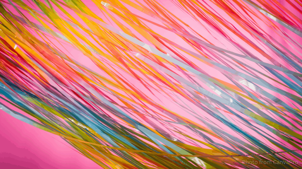 Close up photo of rainbow streamers lying across a pink surface