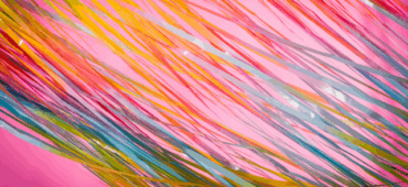 Close up photo of rainbow streamers lying across a pink surface
