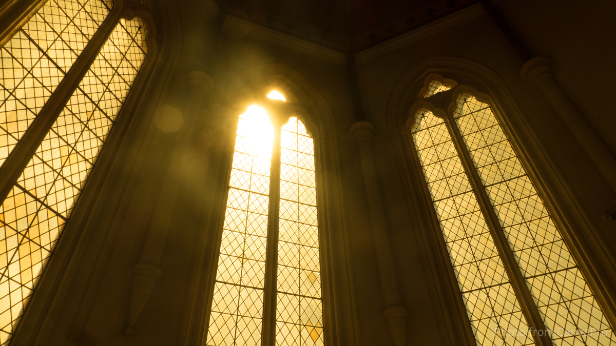 Photo showing sunlight streaming through the imposing windows of a church.