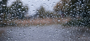 Close up photo of raindrops on a window blurring the view outside