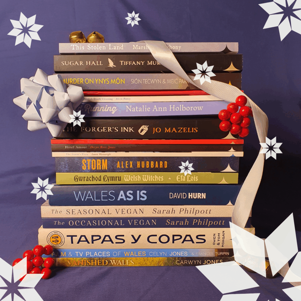 Christmas stack of titles featured in our Christmas gift guide tied up with ribbon and other festive items.