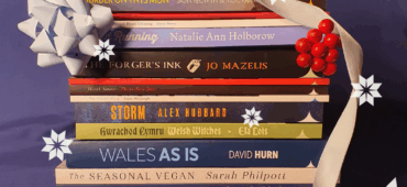 Christmas stack of titles featured in our Christmas gift guide tied up with ribbon and other festive items.