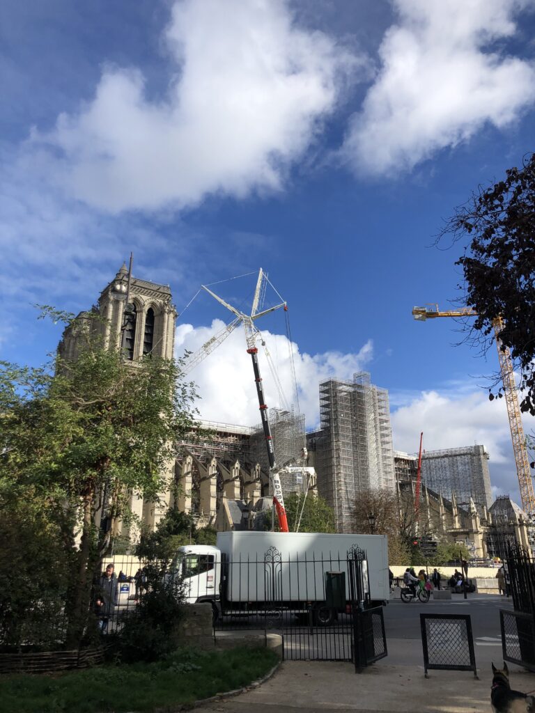 Photo of Notre-Dame cathedral being rebuilt beneath a bright blue sky.