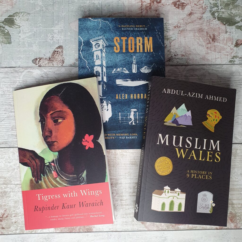 Photo of three books laid out against a wood-effect background