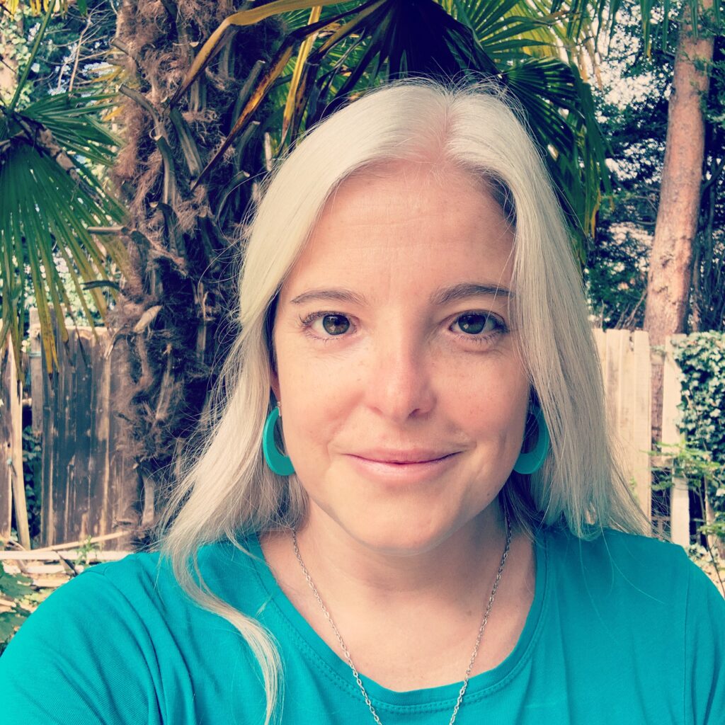Photo of Sara Erddig sat outside. She is smiling at the camera and is wearing a blue top.