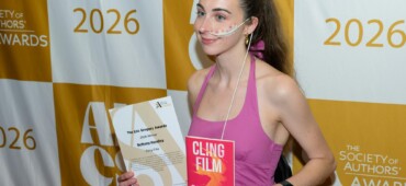 Photo of Bethany Handley at the award ceremony holding a copy of her book and her certificate.