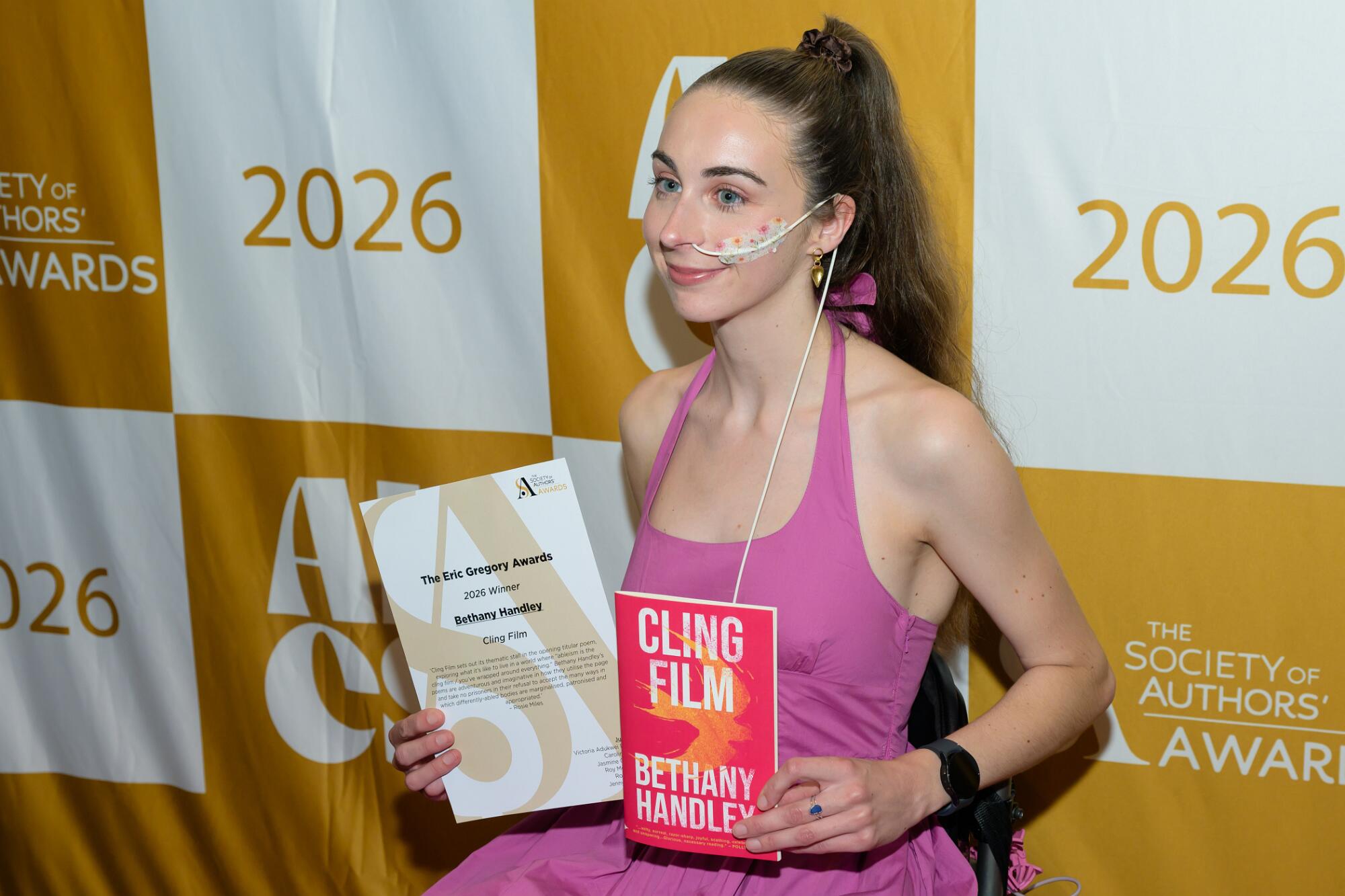 Photo of Bethany Handley at the award ceremony holding a copy of her book and her certificate.