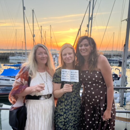Photo of Zoe, Laura and Bronwen standing in front of the harbour with Laura's award.
