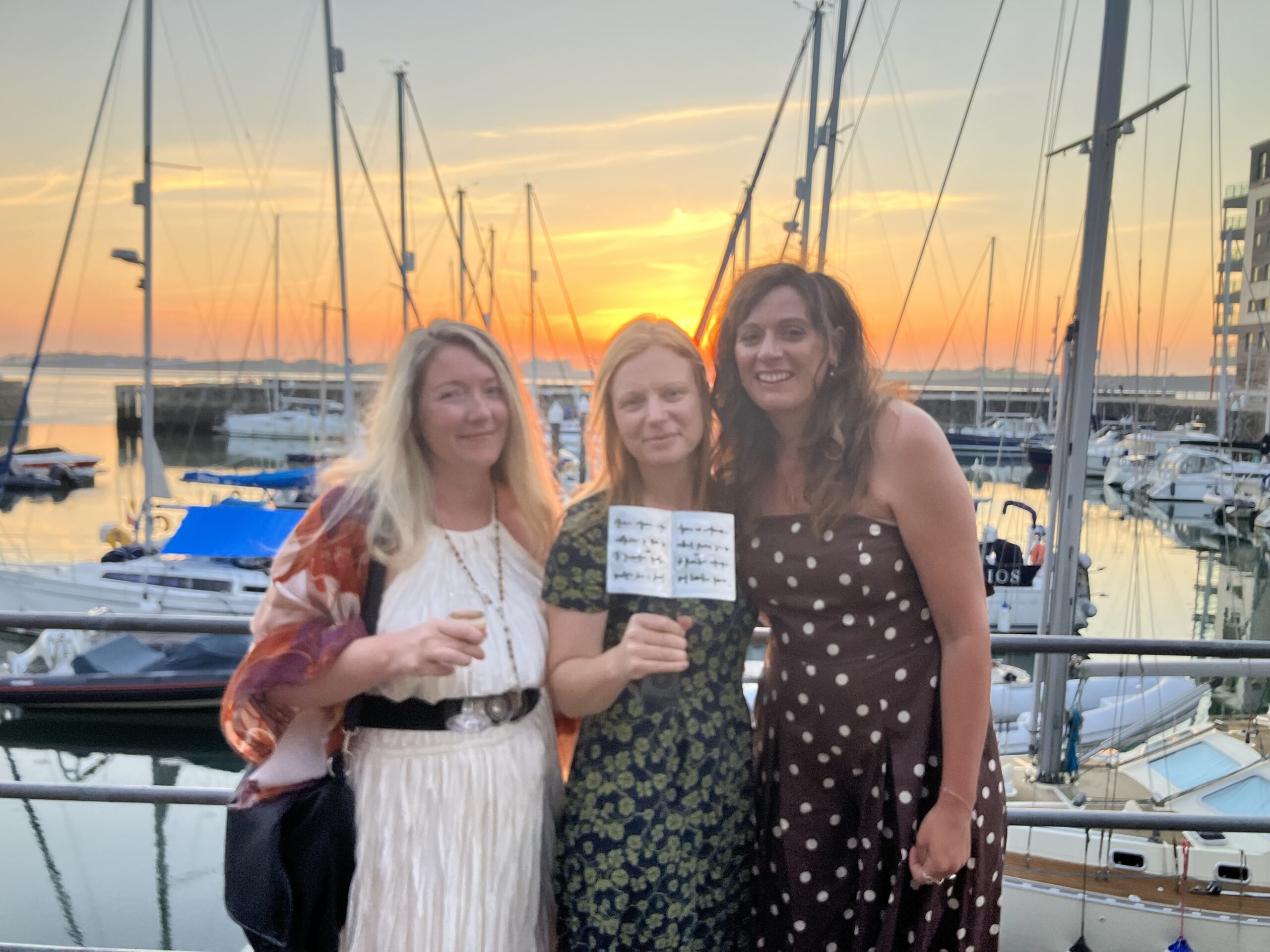 Photo of Zoe, Laura and Bronwen standing in front of the harbour with Laura's award.