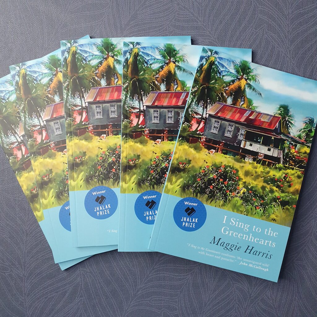 Photo showing copies of I Sing to the Greenhearts fanned out against a blue textured background.