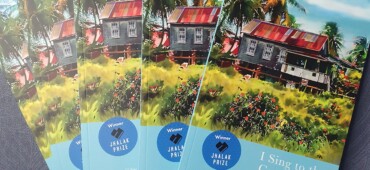 Photo showing copies of I Sing to the Greenhearts fanned out against a blue textured background.